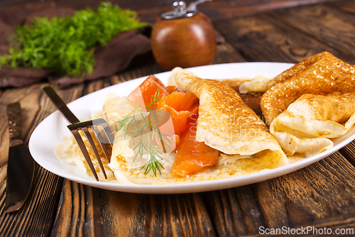Image of Pancakes with salmon (trout). Thin, not sweet blinchiki stuffed with red fish.