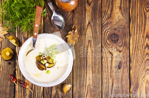 Image of On the wooden table, there is a cream soup with fresh mushrooms as the base