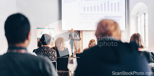 Image of Speaker giving a talk in conference hall at business event. Rear view of unrecognizable people in audience at the conference hall. Business and entrepreneurship concept.