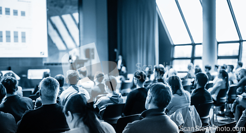 Image of Speaker giving a talk in conference hall at business event. Business and entrepreneurship concept. Blue toned black and white image.