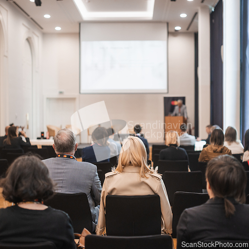 Image of Speaker giving a talk in conference hall at business event. Rear view of unrecognizable people in audience at the conference hall. Business and entrepreneurship concept.