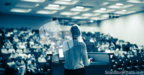 Image of Female speaker giving a talk on corporate business conference. Unrecognizable people in audience at conference hall. Business and Entrepreneurship event.
