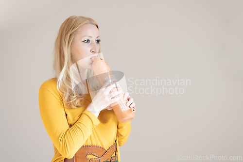 Image of Portrait of female musician playing on traditional clay flute. Woman playing ocarina.