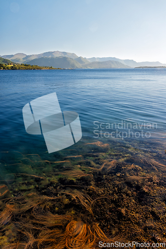 Image of Calm waters of a serene lake framed by distant mountains under a