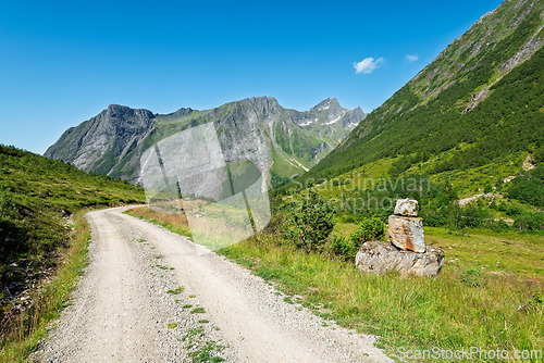 Image of Scenic dirt road winding through mountains under clear blue sky 