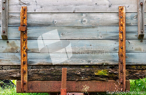 Image of Old wooden cart with rusty metal brackets in a rural setting dur