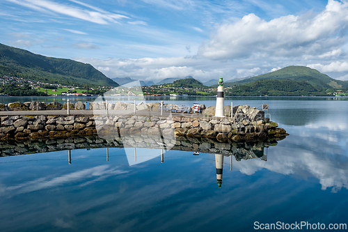 Image of Scenic harbor view with lighthouse and mountains reflecting on c