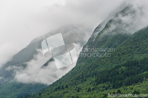 Image of Lush green mountains shrouded in fog with wisps of clouds in a s