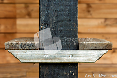 Image of Wooden shelf mounted on a black pillar in a rustic wooden cabin 