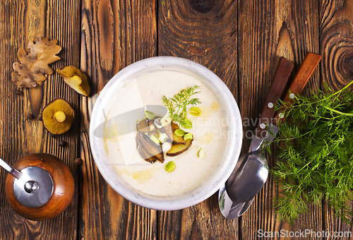 Image of On the wooden table, there is a cream soup with fresh mushrooms as the base
