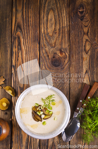 Image of On the wooden table, there is a cream soup with fresh mushrooms as the base
