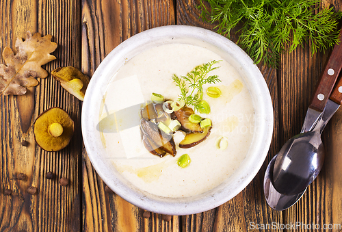 Image of On the wooden table, there is a cream soup with fresh mushrooms as the base