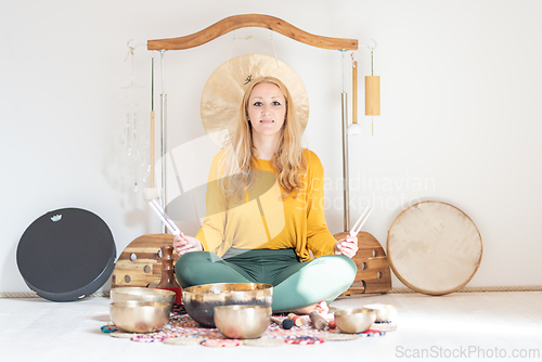 Image of Young cheerful woman performing music therapy session with traditional instruments. Sound meditation, body healing. Seven chakras. Healthcare recreation process.