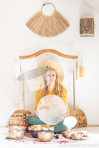 Image of Young cheerful woman performing music therapy session with traditional instruments. Sound meditation, body healing. Seven chakras. Healthcare recreation process.