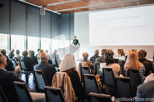 Image of Speaker giving a talk in conference hall at business event. Rear view of unrecognizable people in audience at the conference hall. Business and entrepreneurship concept.