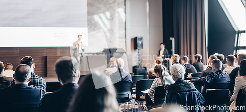 Image of Speaker giving a talk in conference hall at business event. Rear view of unrecognizable people in audience at the conference hall. Business and entrepreneurship concept.