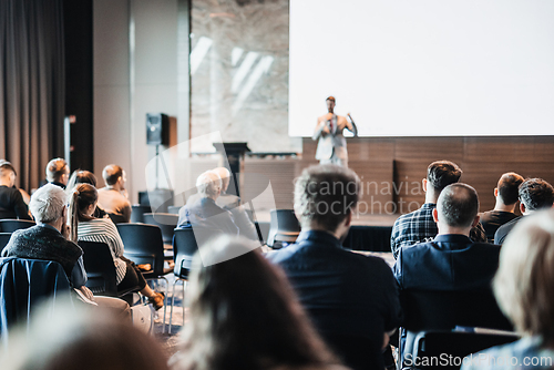 Image of Speaker giving a talk in conference hall at business event. Rear view of unrecognizable people in audience at the conference hall. Business and entrepreneurship concept.