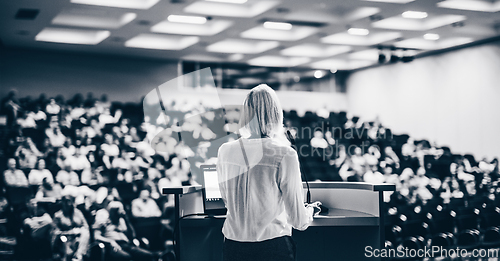 Image of Female speaker giving a talk on corporate business conference. Unrecognizable people in audience at conference hall. Business and Entrepreneurship event.