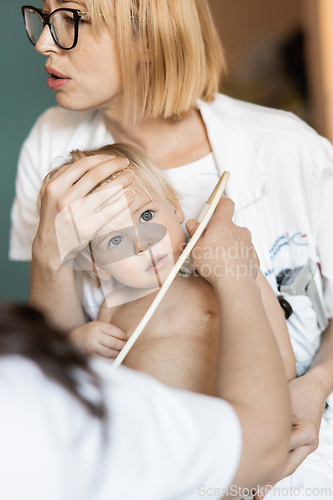Image of Small child being checked for heart murmur by heart ultrasound exam by cardiologist as part of regular medical checkout at pediatrician.