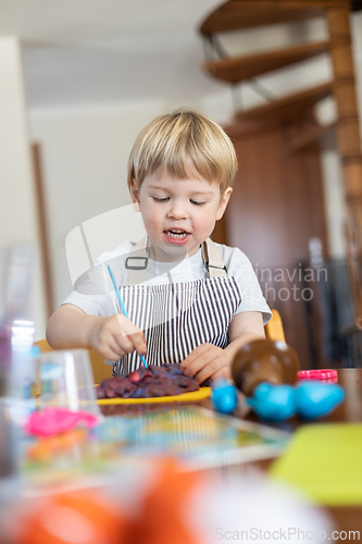 Image of Blond boy sculpts from plasticine at home at the table. The idea and concept of the school, home education and developmental activities.
