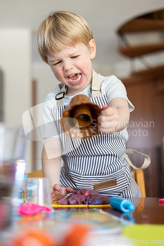 Image of Blond boy sculpts from plasticine at home at the table. The idea and concept of the school, home education and developmental activities.
