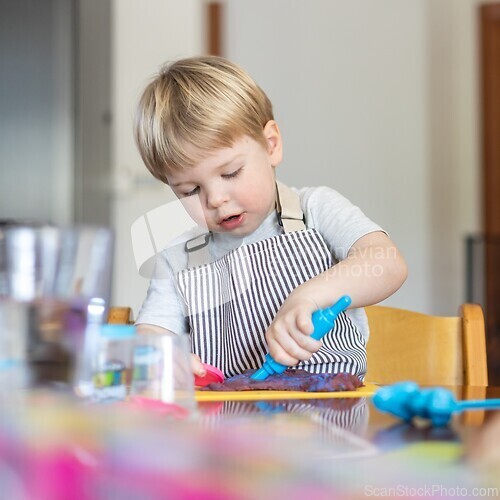 Image of Blond boy sculpts from plasticine at home at the table. The idea and concept of the school, home education and developmental activities.