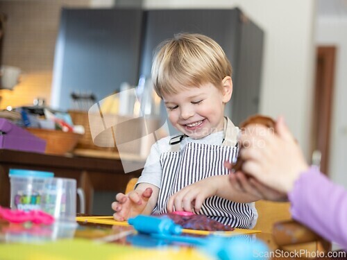 Image of Blond boy sculpts from plasticine at home at the table. The idea and concept of the school, home education and developmental activities.