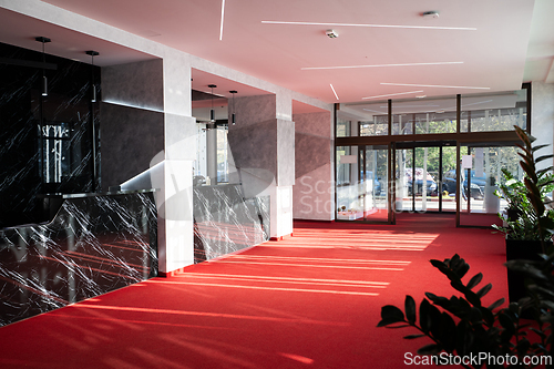 Image of Modern hotel lobby with red carpet and decorative plants
