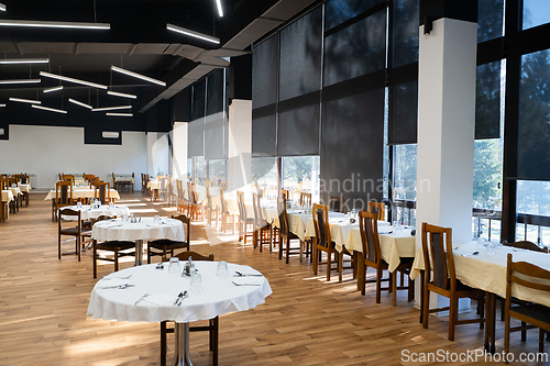 Image of Restaurant interior with large sunlit windows and wooden chairs