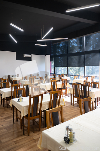 Image of Restaurant interior with large sunlit windows and wooden chairs