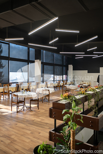 Image of Restaurant interior with large sunlit windows and wooden chairs