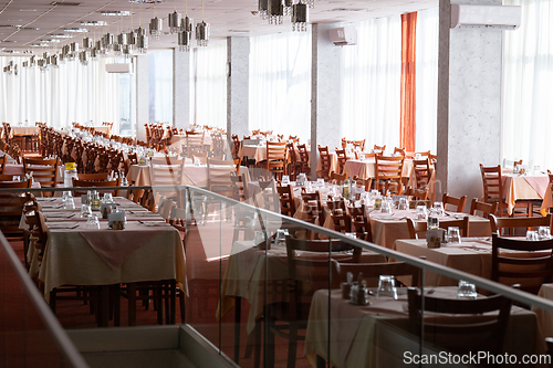 Image of Empty restaurant dining hall with arranged tables and chairs