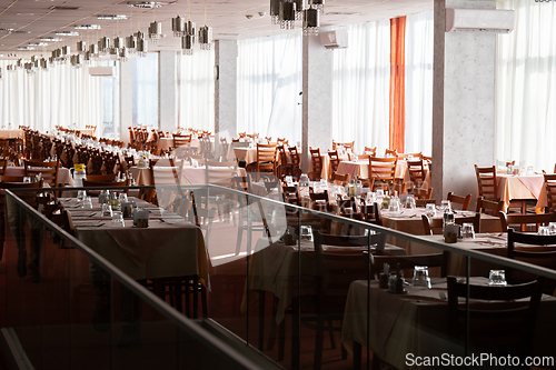 Image of Empty restaurant dining hall with arranged tables and chairs