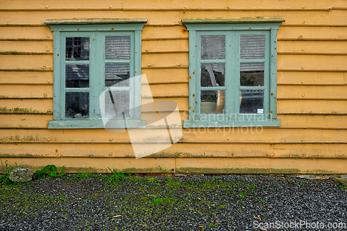Image of Old yellow building with turquoise windows captures rustic charm