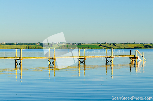 Image of Evening reflections on a serene ocean pier with calm waters and 