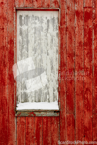 Image of Weathered red wooden wall with a blank window frame covered in s