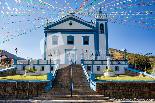Image of Church of Our Lady Help Of adorned with colorful festive flags against a blue sky. Ilhabela, Sao Paulo Brazil.