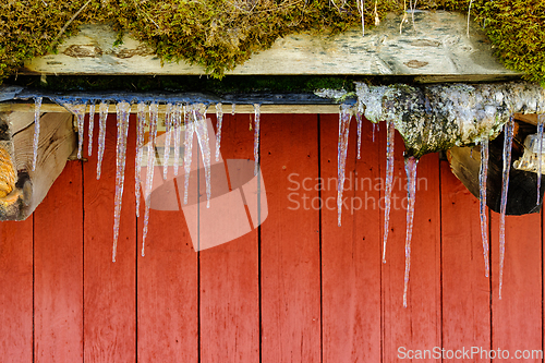 Image of Icicles hanging from a rustic wooden roof in a cold winter setti