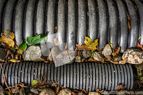 Image of Detailed view of black drainage pipes surrounded by stones and a