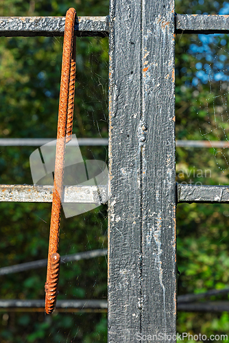 Image of Rusty metal bar hanging from a weathered structure surrounded by