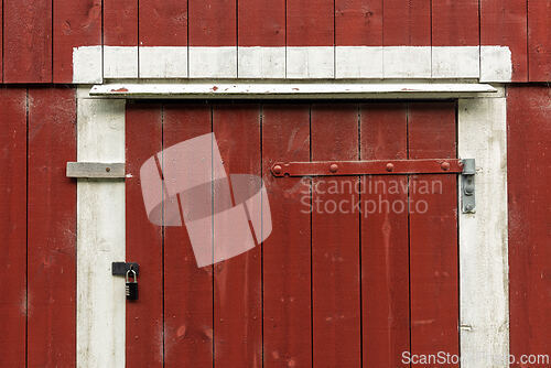 Image of Weathered red barn door with a rustic charm in a countryside set