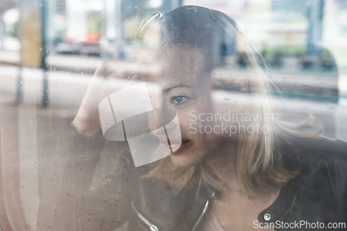 Image of Woman traveler contemplating outdoor view from window of train. Young lady on commute travel to work sitting in bus or train.