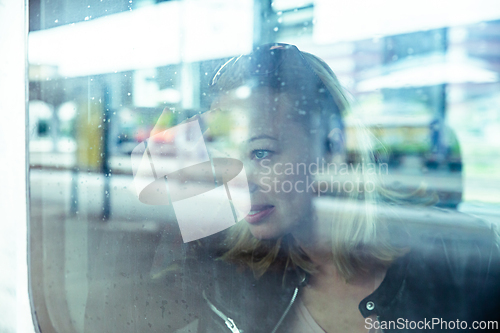 Image of Woman traveler contemplating outdoor view from window of train. Young lady on commute travel to work sitting in bus or train.