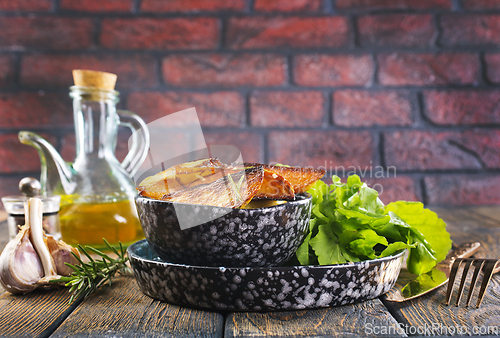 Image of Bowl with baked potatoes on wooden background