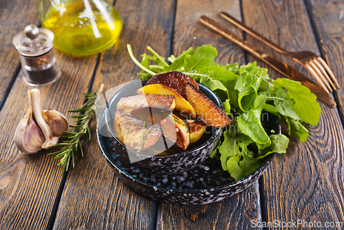 Image of Bowl with baked potatoes on wooden background