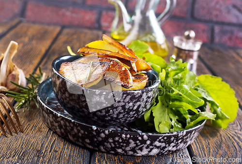 Image of Bowl with baked potatoes on wooden background
