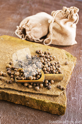 Image of Pile of Black peppercorns seeds on stone board
