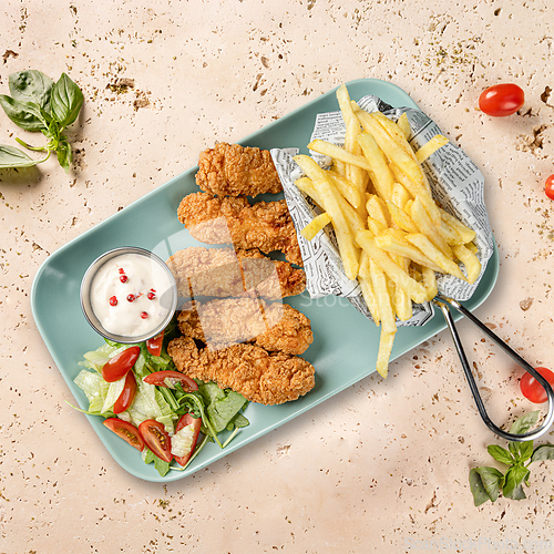 Image of Breaded chicken strips served with french fries
