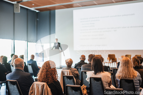 Image of Speaker giving a talk in conference hall at business event. Rear view of unrecognizable people in audience at the conference hall. Business and entrepreneurship concept.