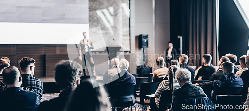 Image of Speaker giving a talk in conference hall at business event. Rear view of unrecognizable people in audience at the conference hall. Business and entrepreneurship concept.
